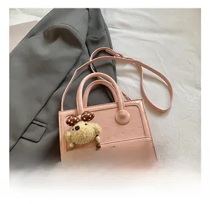 Detail of pink faux leather crossbody bag with 3D bear embossing and plush charm