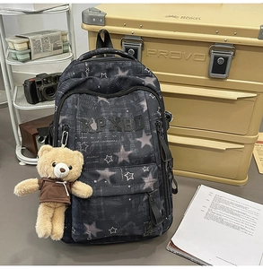 Detailansicht grauer Rucksack mit Sternenmuster, Stickerei und süßem Bärenanhänger-Dekor