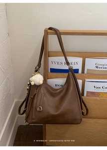 Brown retro hobo bag with adjustable strap and cute sheep charm on a wooden rack