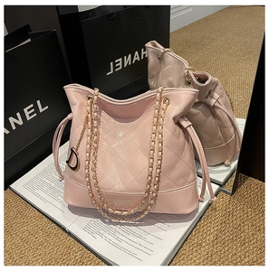 Macro view of pink quilted bucket bag with shiny patent leather and golden D-charm detail