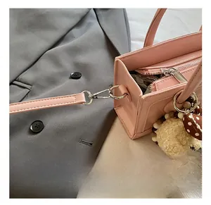 Detailed close-up of pink leather handbag with metal hook and dotted bow bear charm