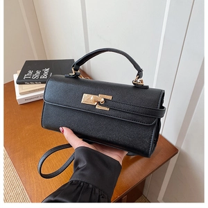 Détail d'un sac à main en cuir noir texturé avec fermoir doré et bandoulière réglable