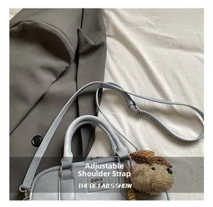 Détails de la bandoulière réglable et du pendentif ours sur le sac à main bleu-gris