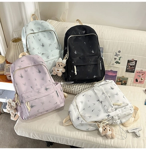 Détail rapproché des sacs à dos en nylon imprimé papillon avec pendentif ours