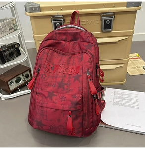 Detail eines roten Rucksacks mit Sternenmuster, Reißverschlüssen und Retro-Schuldekor