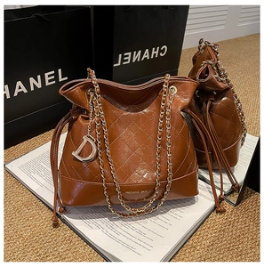 Close-up of quilted leather bucket bag with gold-tone chain and D-letter charm detail