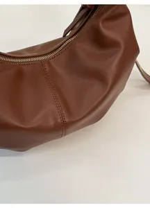 Detailed close-up of brown leather bag showing rich texture and fine double-needle stitching