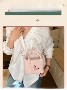 Détail d'un mini sac seau rose avec broderie de chien et fine bandoulière élégante