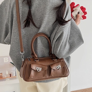 Detail of dark brown baguette bag with dual front pockets and silver G-shaped hardware
