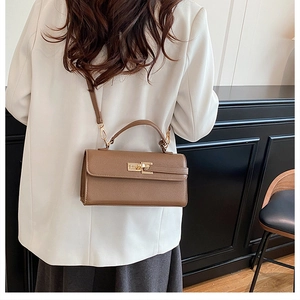 Sac bandoulière marron porté par un mannequin en blazer blanc et jupe grise