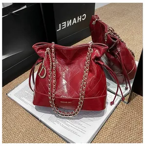 Detail of red quilted leather bucket bag with gold chain strap and D-ring charm