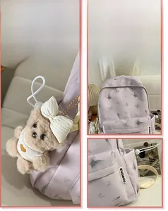 Détail d'un sac à dos d'écolier violet avec motif papillon et pendentif ours en peluche