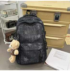 Detail eines Camouflage Rucksacks mit Sternenmuster, Stickerei und Plüschbär Anhänger