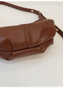Detail of the pleated bottom design and textured brown leather on this minimalist handbag