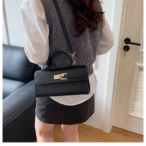 Détail du sac à main en cuir noir avec fermoir doré et bandoulière amovible