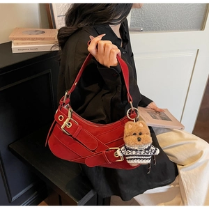 Detail of dark red vintage baguette bag with gold buckle and cute bear charm accessory