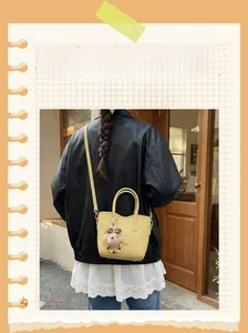 Close-up of a yellow bucket bag with lychee texture and a cute bear charm accessory