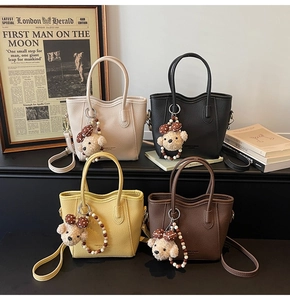 Detail view of stylish bucket bags in four colors with cute bear charms and straps
