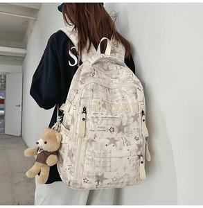 Detail eines beigen Studentenrucksacks mit Bärenanhänger und Sternen auf Canvas-Stoff