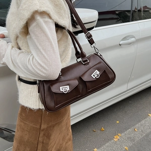 Detail of dark brown baguette bag with dual front pockets and silver ring hardware accents