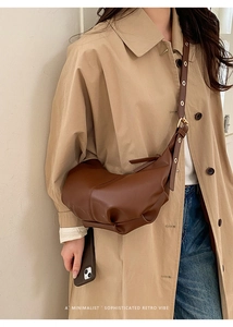 Detailed close-up of dark brown soft leather half-moon crossbody bag with pleat design