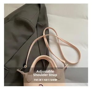 Détail de la bandoulière réglable et des broderies sur le sac seau beige pour femmes