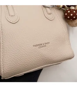 Detail of beige bucket bag showing litchi grain texture and plush polka dot charm