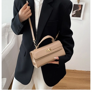 Détail du sac à main beige porté par un mannequin vêtu d'un blazer noir élégant