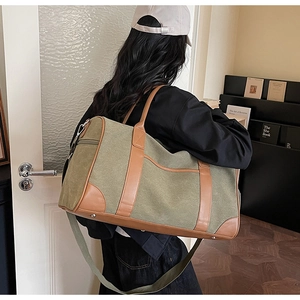 Detail view of large canvas travel bag with leather accents and adjustable shoulder strap