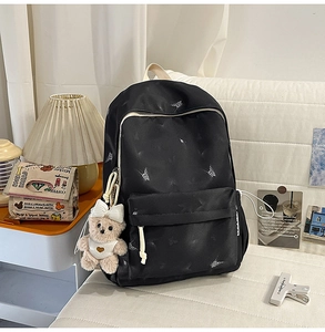 Détail du sac à dos en nylon noir avec motifs papillons et pendentif ours peluche