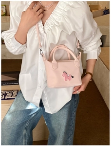 Détail d'une broderie de cheval sur un sac à bandoulière rose avec lanière en cuir