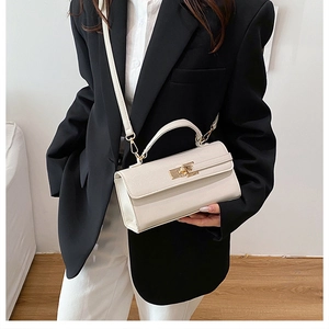 Détail d'un sac bandoulière crème avec fermoir rotatif doré et texture grainée