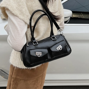 Detail shot of a black leather Boston bag with silver buckles worn as a shoulder bag