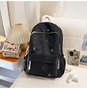 Détail d'un sac à dos en nylon noir avec imprimé papillon blanc et étiquette de marque