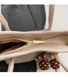 Detail of golden zipper and lychee grain faux leather on the beige bucket bag