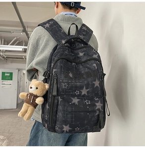 Detailansicht eines grauen Rucksacks mit Sternmuster und süßem Bären-Anhänger-Dekor