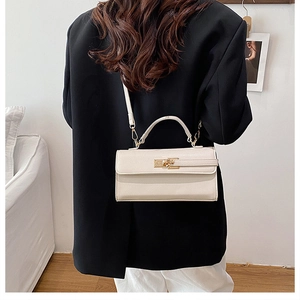 Sac à main en cuir blanc avec fermoir pivotant en métal sur blazer noir chic et rétro