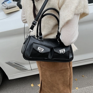 Detail of black leather baguette bag with dual silver rings and adjustable shoulder strap