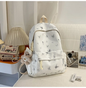 Détail du sac à dos en nylon imprimé papillon avec un pendentif ours en peluche