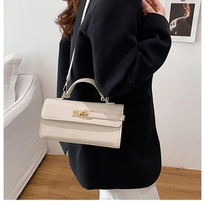 Détail du sac beige en cuir grainé avec fermoir rotatif doré et poignée élégante