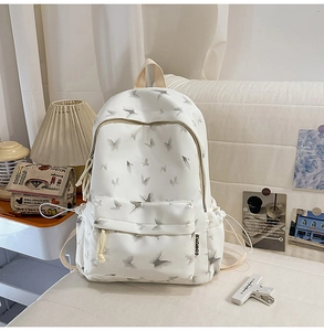 Détail d'un sac à dos blanc en nylon avec imprimé papillon gris sur un canapé