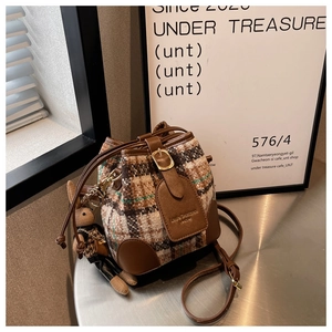 Detail van geruite emmertas met tweed textuur, leren bies en een schattige konijnenhanger