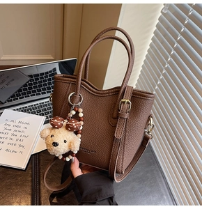 Close-up of dark brown lychee leather bucket bag with cute plush puppy charm
