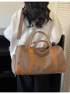 Large capacity canvas travel bag with leather accents shown being carried by a model
