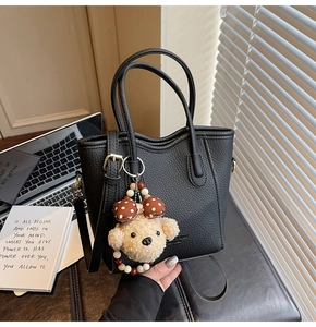 Close-up of black lychee grain bucket bag with a cute teddy dog ribbon charm