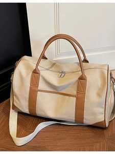 Large beige canvas travel bag with brown leather trim shown from a stylish top angle
