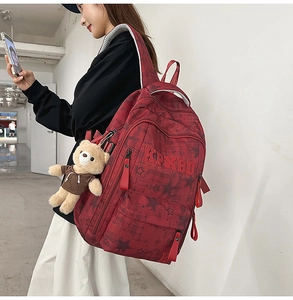 Detail eines dunkelroten Rucksacks mit Sternmuster, KPXBD-Stickerei und Bären-Anhänger