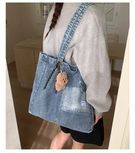 Dettaglio della borsa tote in denim a righe con tasca laterale e ciondolo orso