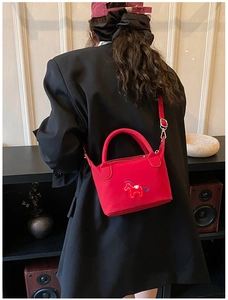 Détail du mini sac cabas rouge avec broderie cheval porté sur une veste noire