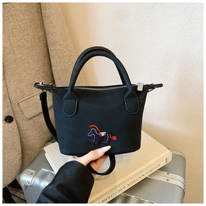 Gros plan du sac seau noir en cuir avec broderie de poney coloré et fermeture éclair